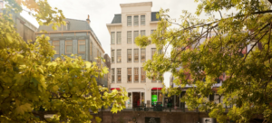 The facade of a canal house in Utrecht, home to the Skuridat office, seen through autumnal tree branches.