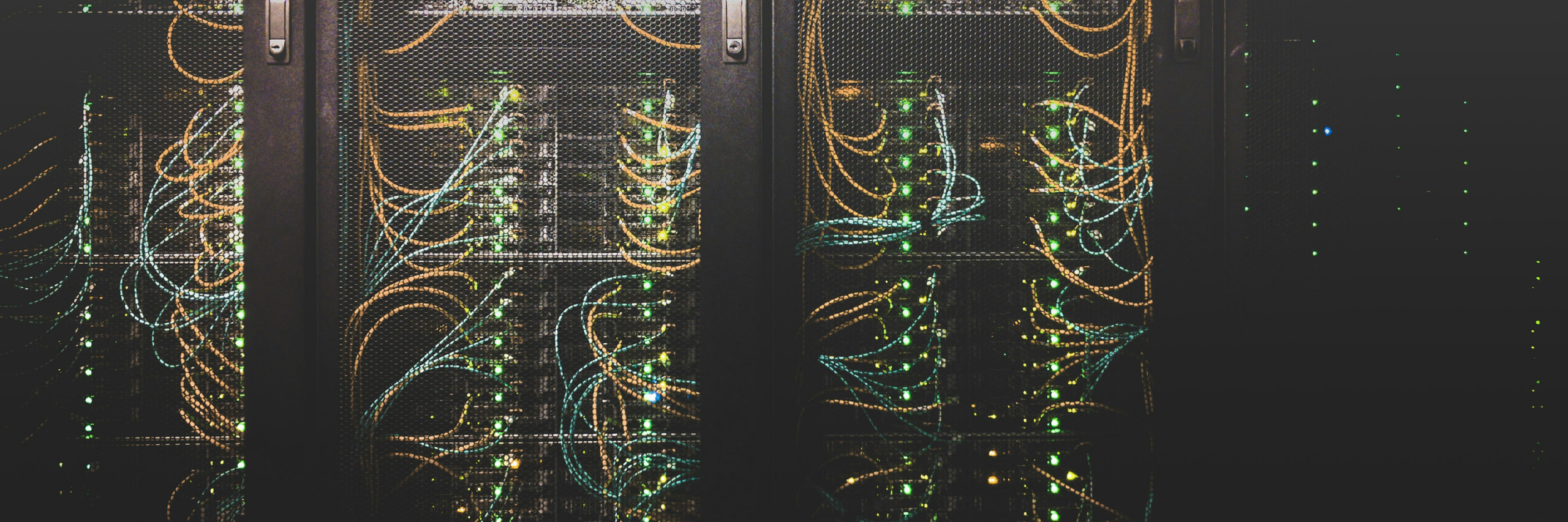 Rows of server racks in a data center, dense with fiber and network cabling